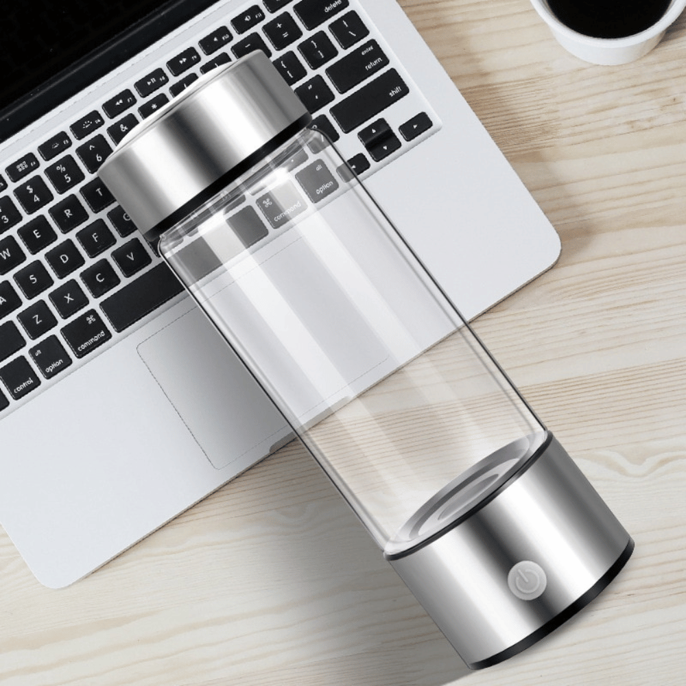 Portable Hydrogen Water Bottle beside laptop with transparent body for office and travel hydration