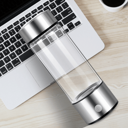 Portable Hydrogen Water Bottle beside laptop with transparent body for office and travel hydration